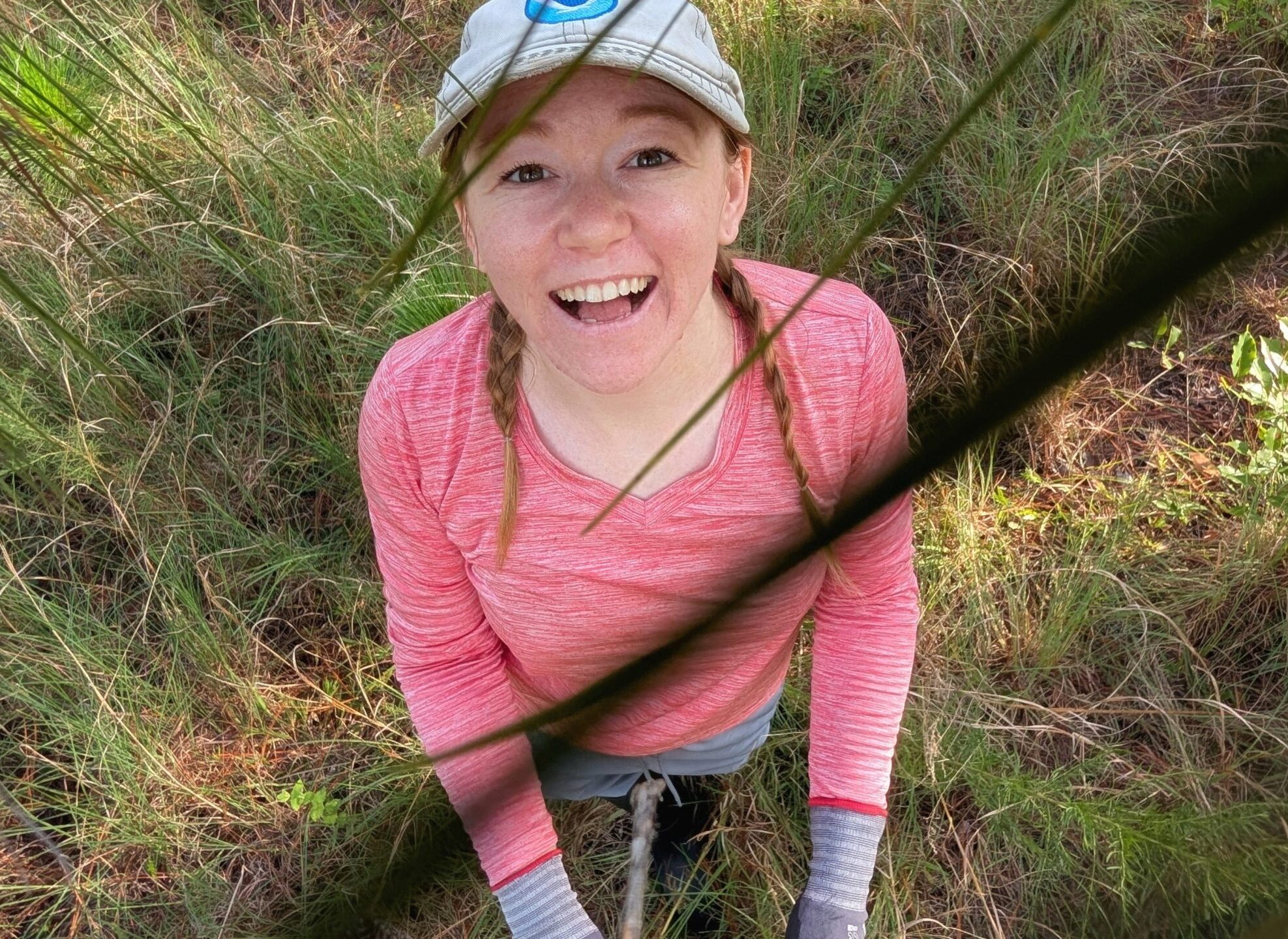 A woman smiles through pine needles.