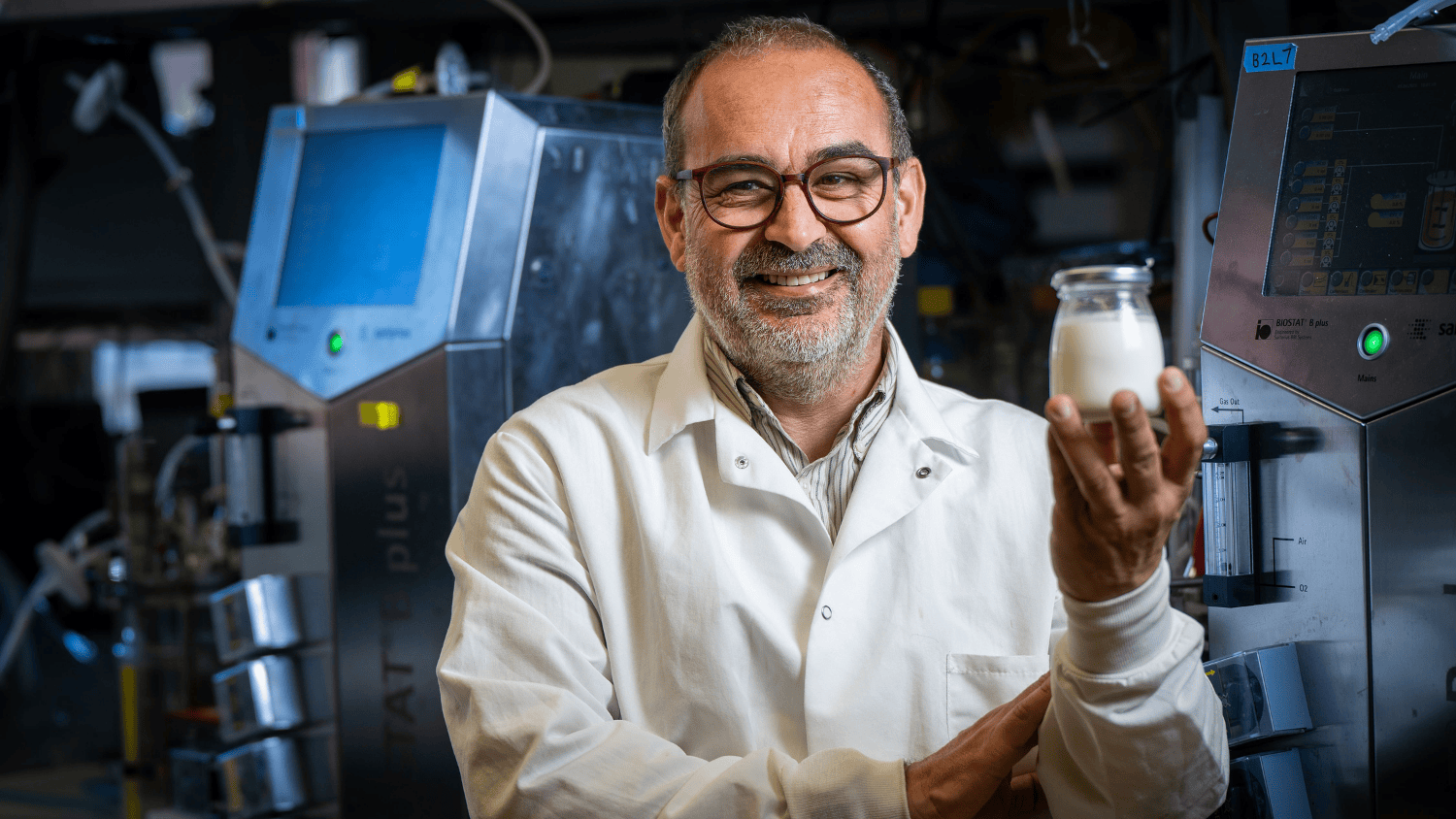 A man holds a glass jar of milk in a laboratory.